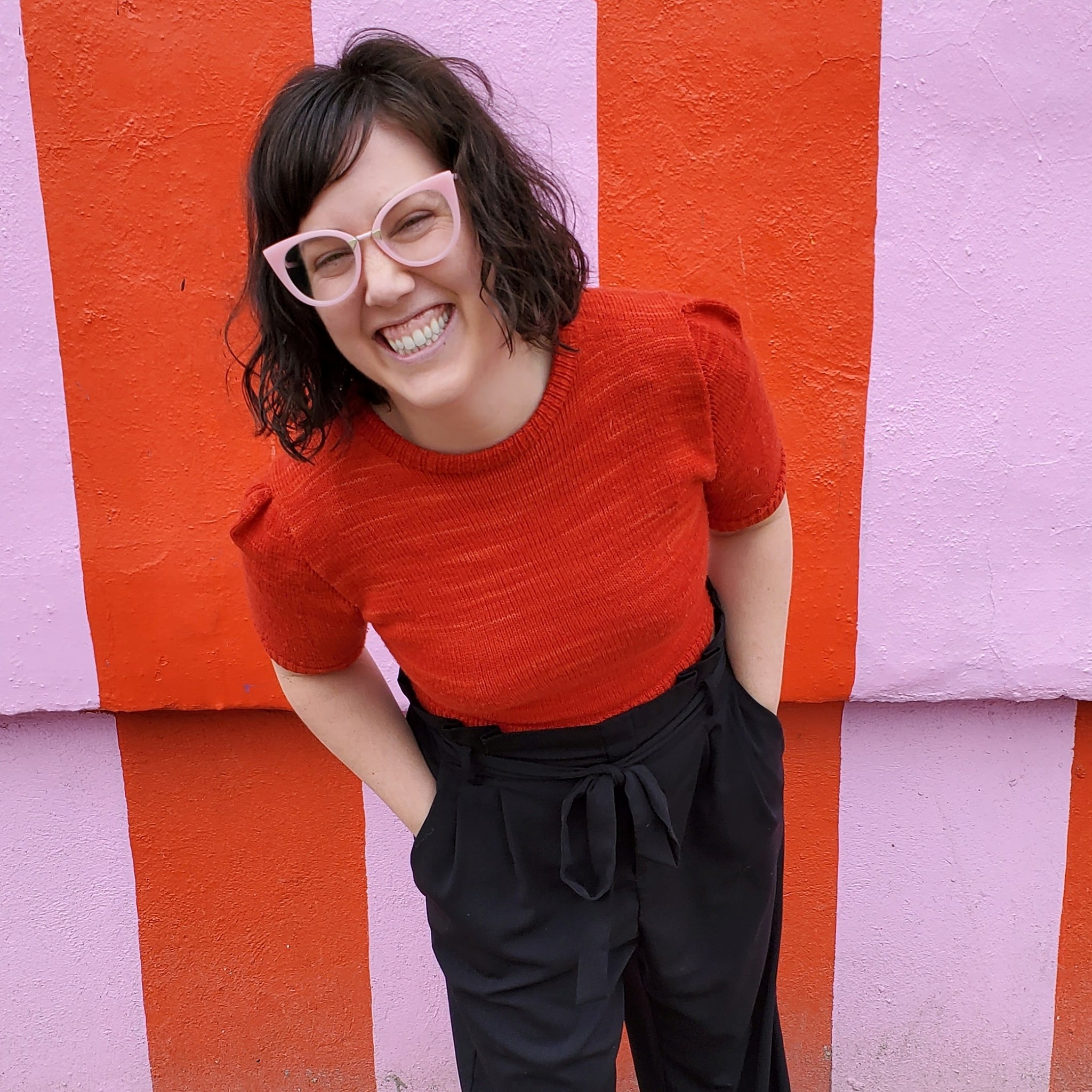 Picture of Nicole McDonald leaning forward laughing in front of a mural